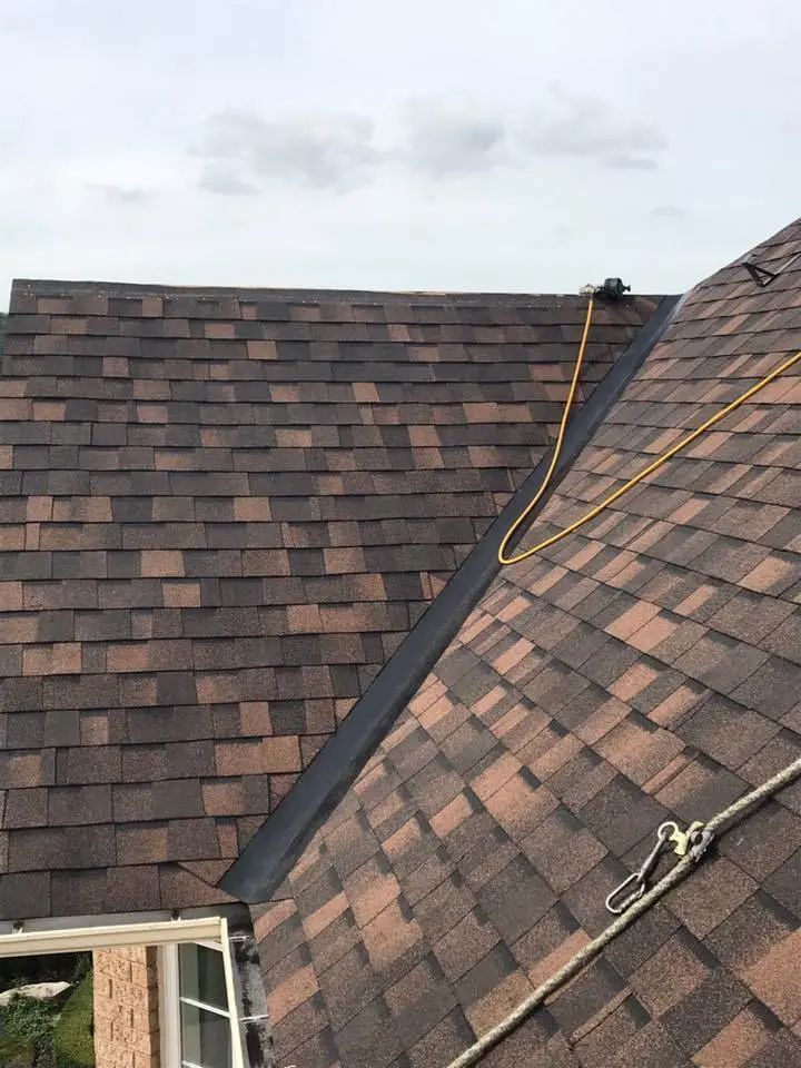 Brown architectural shingles being installed along a ridge